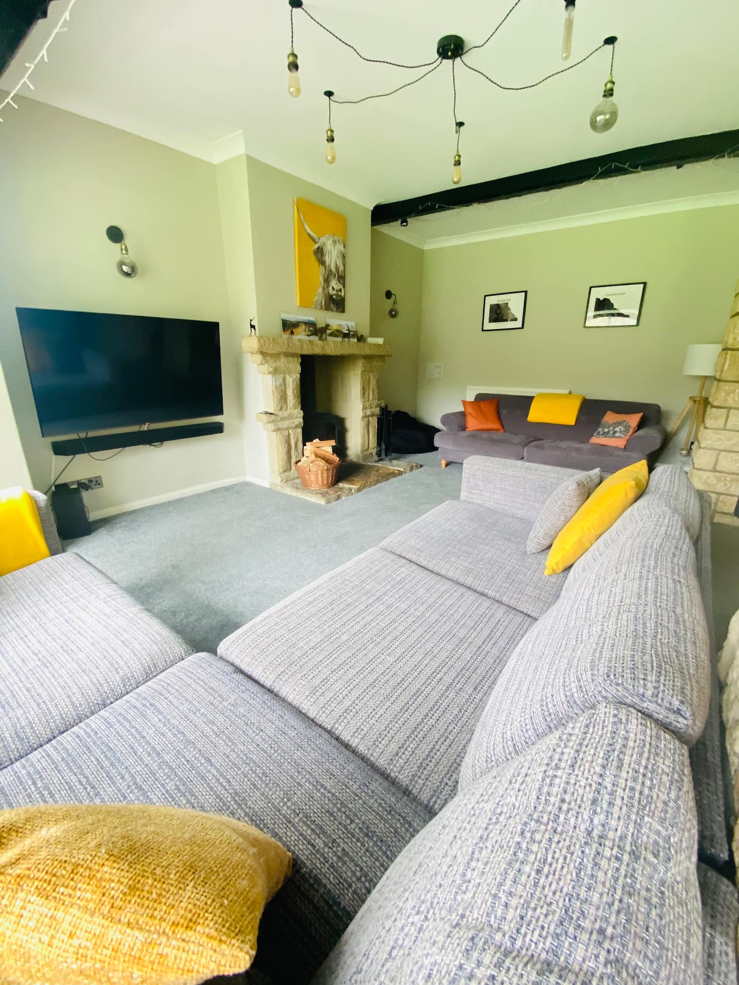 Open-plan living room with deep sofas, wood-burning stove and garden views