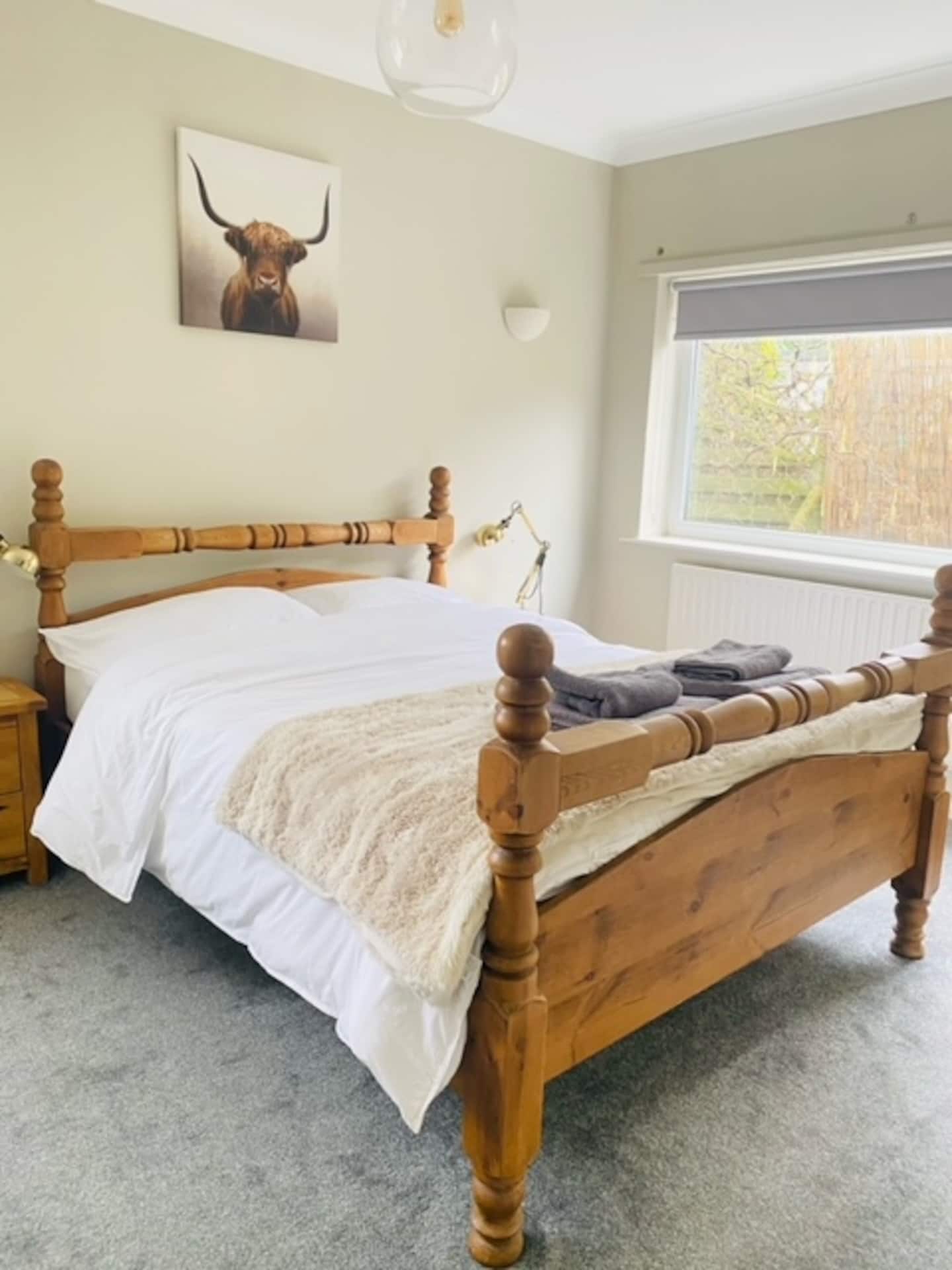 Master double bedroom with white linen, soft lighting and countryside views